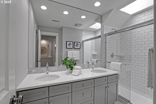 bathroom featuring double vanity, a stall shower, visible vents, and a sink