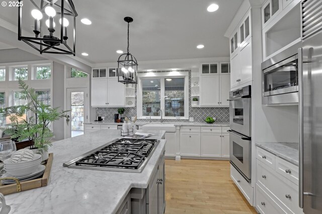 kitchen featuring backsplash, a notable chandelier, built in appliances, and a sink