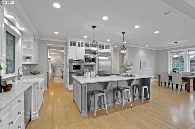 kitchen featuring a large island, white cabinetry, crown molding, decorative backsplash, and built in appliances