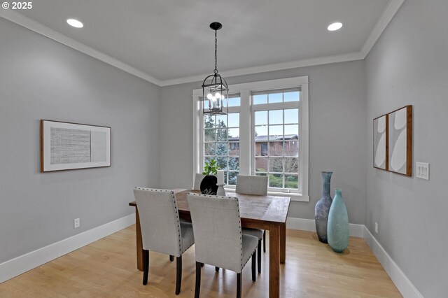 dining space featuring light wood-style flooring, baseboards, and ornamental molding