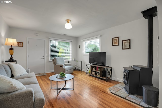 living room with baseboards, visible vents, a wood stove, and light wood-style floors