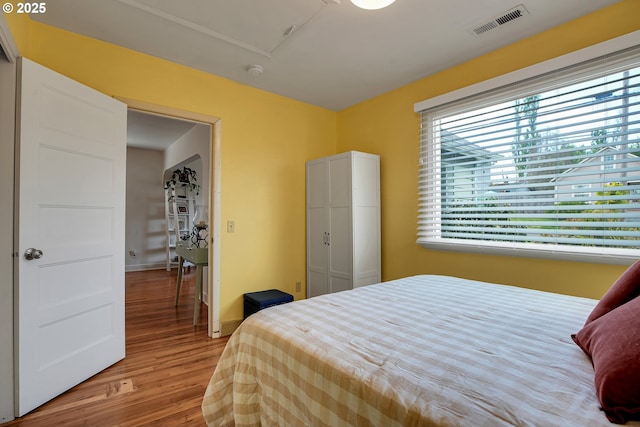 bedroom featuring baseboards, light wood finished floors, and visible vents
