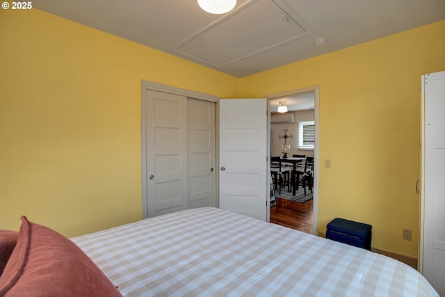 bedroom with an AC wall unit, attic access, and a closet
