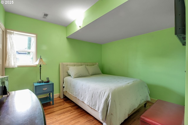 bedroom featuring baseboards, visible vents, and wood finished floors