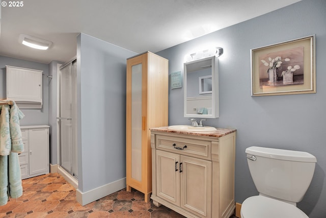 bathroom with vanity, toilet, baseboards, and a stall shower