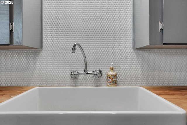 details featuring a sink, wood counters, decorative backsplash, and gray cabinetry