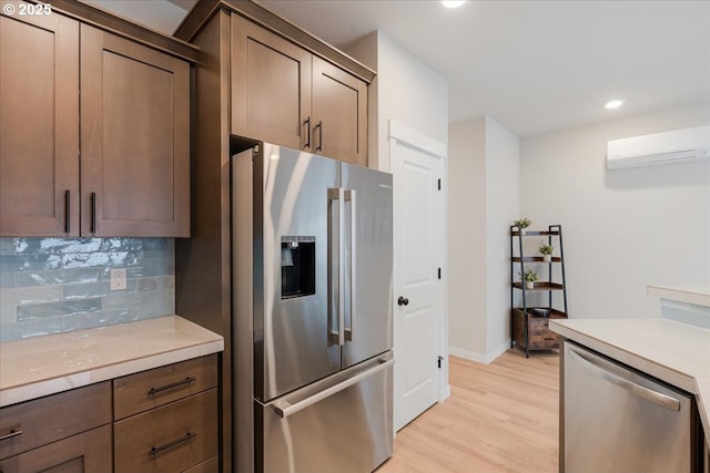 2856 S Nectarine St, Cornelius, OR 97113 - kitchen with appliances with stainless steel finishes, a wall mounted air conditioner, backsplash, light wood-type flooring, and light countertops