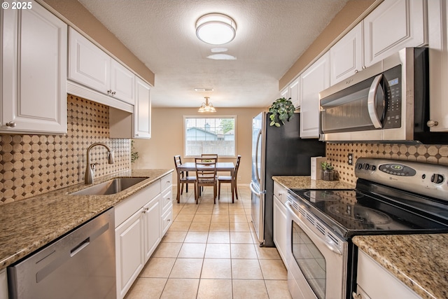 5354 Cody Ave, Eugene, OR 97402 - kitchen featuring stainless steel appliances, white cabinetry, tasteful backsplash, light tile patterned flooring, and a textured ceiling