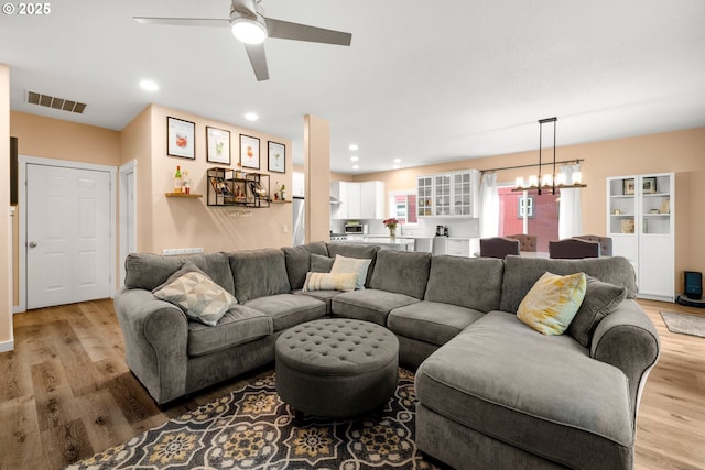 living area featuring a chandelier, light wood-style flooring, ceiling fan, and recessed lighting