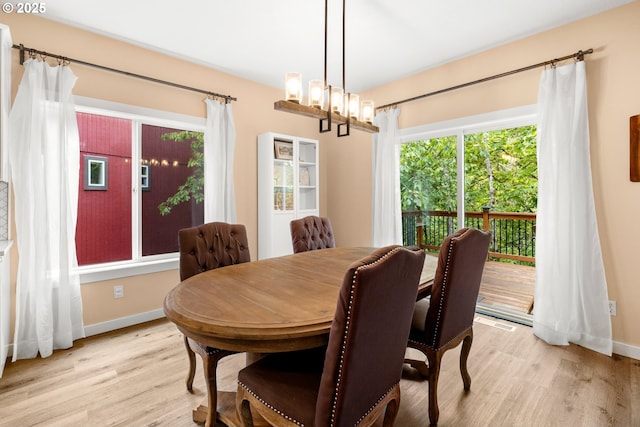 dining room featuring light wood-style floors, healthy amount of natural light, baseboards, and a chandelier