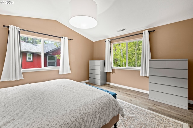 bedroom with multiple windows, wood finished floors, lofted ceiling, and baseboards
