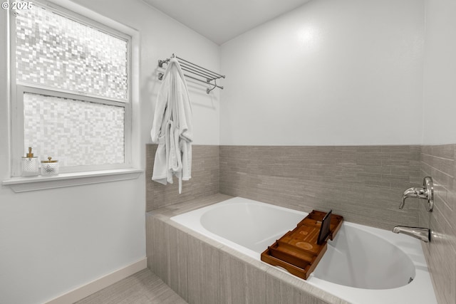 bathroom featuring a garden tub, a sink, and baseboards