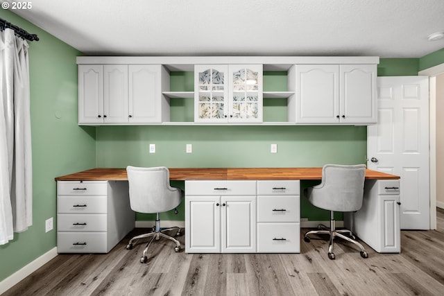 office with built in study area, light wood finished floors, and baseboards
