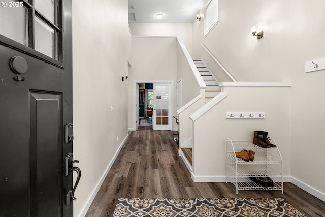 foyer entrance featuring wood finished floors, baseboards, stairs, and a high ceiling
