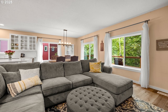 living area featuring a chandelier, wood finished floors, and baseboards