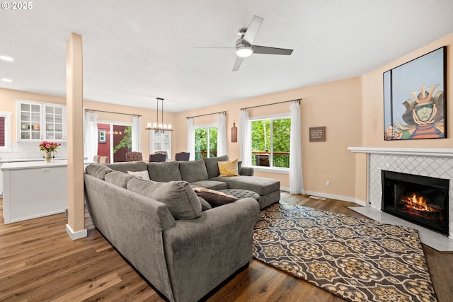 living room with a tile fireplace, ceiling fan, wood finished floors, a chandelier, and recessed lighting