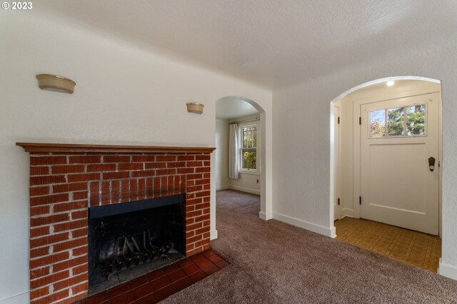 3148 Willamette St, Eugene, OR 97405 - unfurnished living room featuring carpet floors, arched walkways, a fireplace, and baseboards