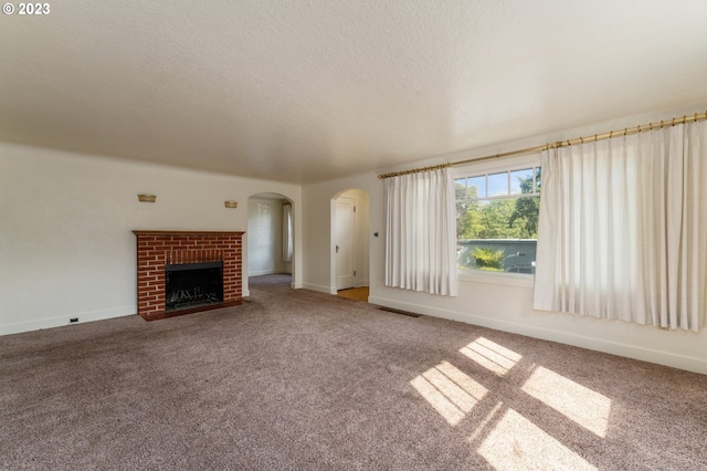 3148 Willamette St, Eugene, OR 97405 - unfurnished living room with carpet, a brick fireplace, arched walkways, baseboards, and a textured ceiling