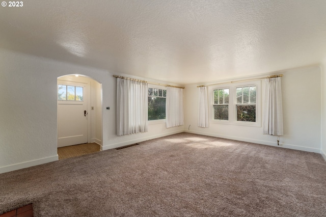 3148 Willamette St, Eugene, OR 97405 - empty room featuring arched walkways, carpet flooring, baseboards, and a textured ceiling