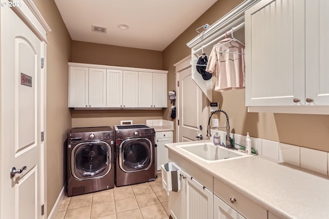 laundry room featuring washing machine and clothes dryer, light tile patterned floors, cabinet space, visible vents, and a sink