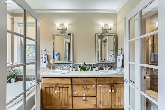 full bath featuring crown molding, a garden tub, a sink, and double vanity