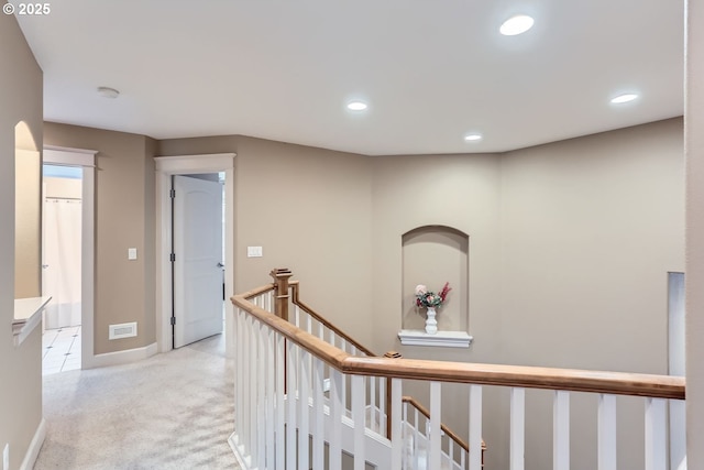 corridor featuring recessed lighting, light colored carpet, visible vents, baseboards, and an upstairs landing