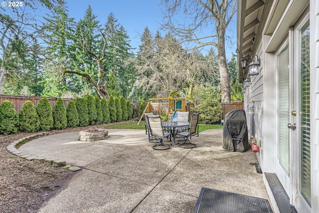 view of patio with an outdoor fire pit, a fenced backyard, and a playground