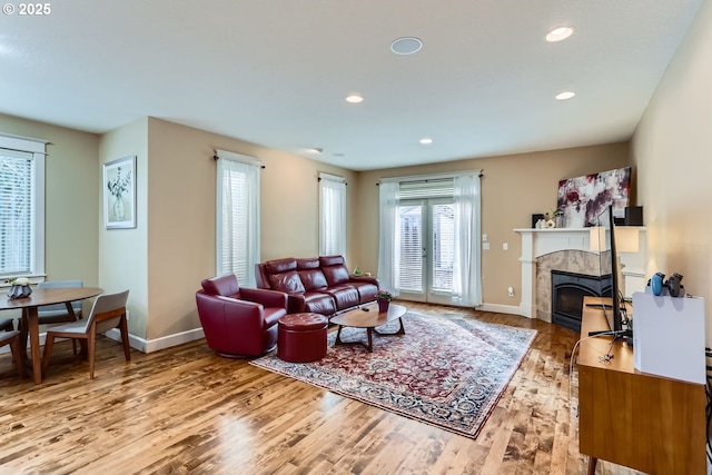 living room featuring a tile fireplace, recessed lighting, baseboards, and wood finished floors