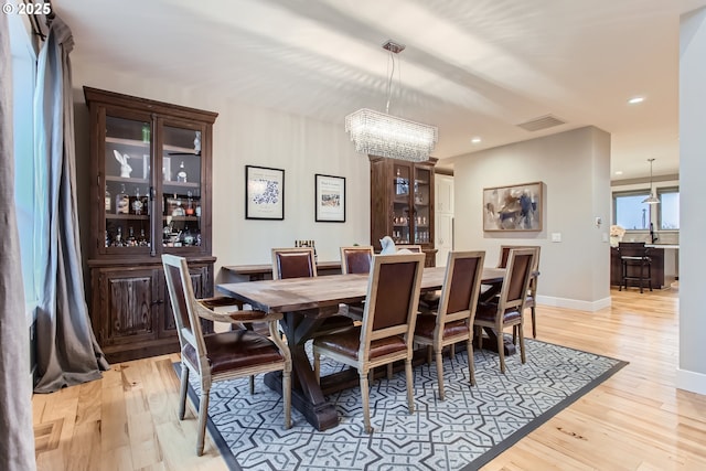 dining room with light wood-type flooring and an inviting chandelier