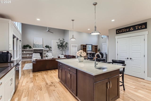 kitchen with pendant lighting, sink, ceiling fan, dark brown cabinets, and white cabinetry