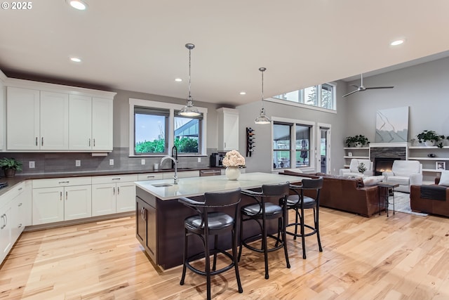 kitchen with white cabinets, pendant lighting, ceiling fan, and a kitchen island with sink