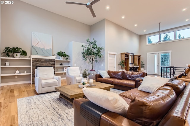 living room featuring ceiling fan, light hardwood / wood-style floors, a towering ceiling, and french doors