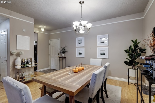 dining space featuring a textured ceiling, an inviting chandelier, and light hardwood / wood-style flooring