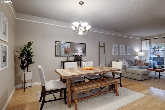 dining room featuring a notable chandelier, light hardwood / wood-style floors, and a textured ceiling