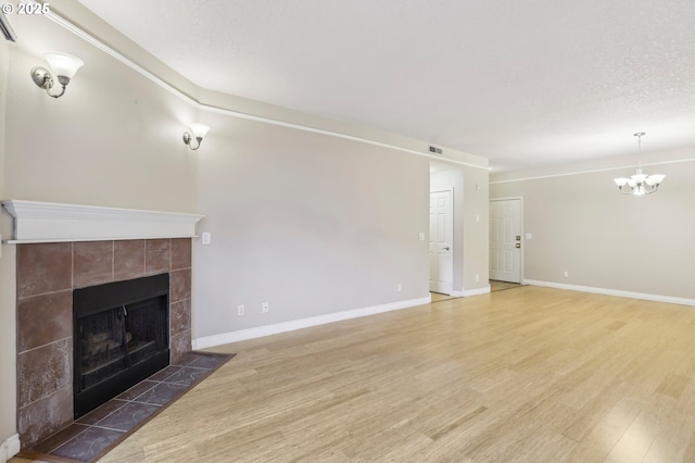 unfurnished living room with baseboards, visible vents, wood finished floors, a textured ceiling, and a fireplace