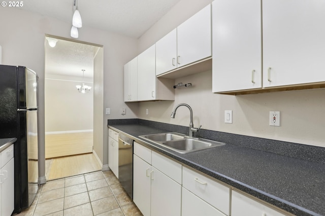 kitchen featuring white cabinets, freestanding refrigerator, a sink, a textured ceiling, and stainless steel dishwasher