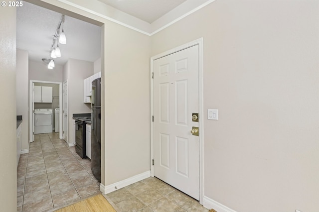 foyer with washer and dryer, baseboards, track lighting, and light tile patterned floors