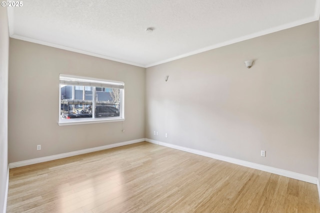 unfurnished room with light wood-style floors, a textured ceiling, baseboards, and crown molding