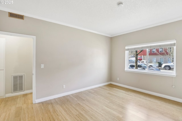 spare room featuring light wood-type flooring, baseboards, and visible vents