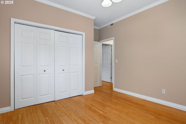 unfurnished bedroom featuring ornamental molding, light hardwood / wood-style floors, and a closet