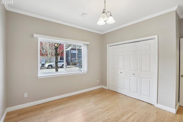 unfurnished bedroom with a notable chandelier, baseboards, and wood finished floors