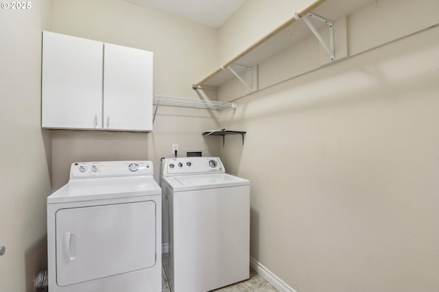 washroom with cabinet space, baseboards, and washing machine and clothes dryer