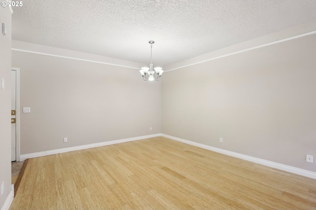 unfurnished room with baseboards, light wood-style flooring, and an inviting chandelier