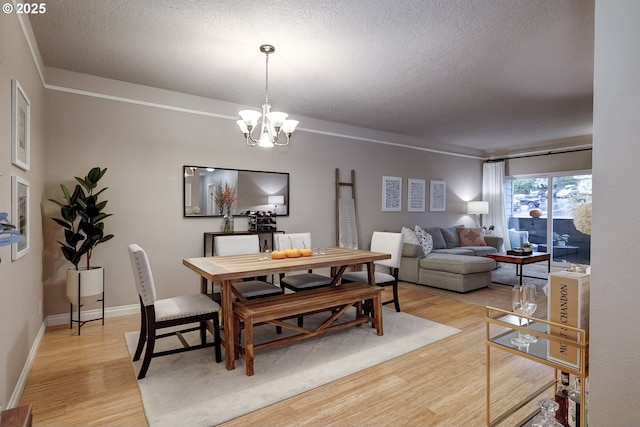 dining room featuring an inviting chandelier, light hardwood / wood-style flooring, and a textured ceiling