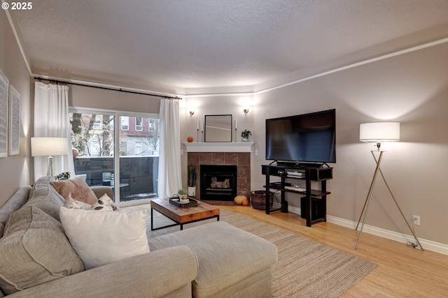 living room with hardwood / wood-style flooring, a tile fireplace, and a textured ceiling