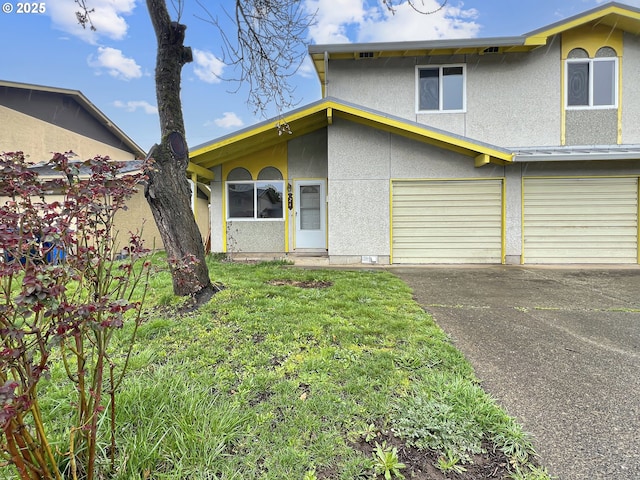 view of front of property featuring stucco siding, a front lawn, an attached garage, and driveway