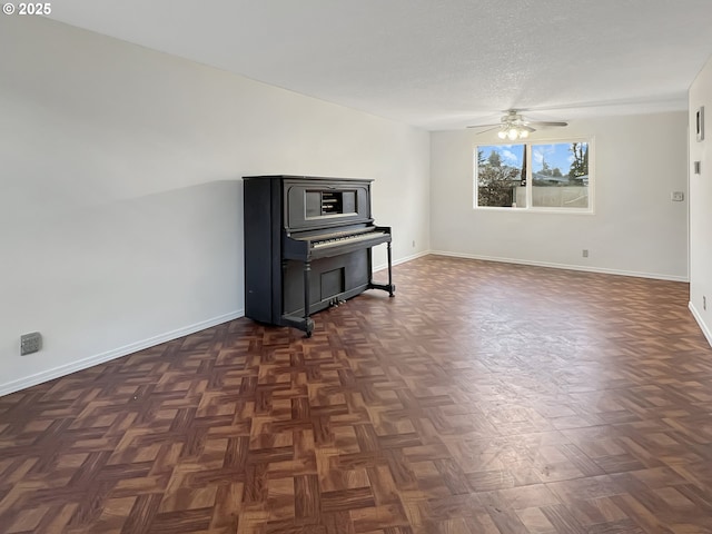 living area with ceiling fan, a textured ceiling, and baseboards