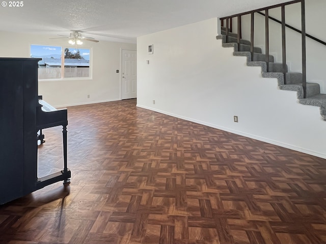 interior space featuring ceiling fan, stairway, baseboards, and a textured ceiling