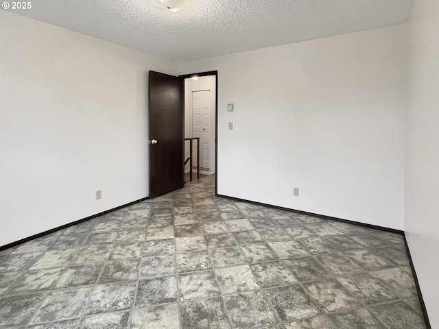 unfurnished room featuring baseboards and a textured ceiling