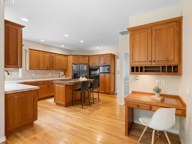 17712 SW 81st Pl, Durham, OR 97224 - kitchen featuring appliances with stainless steel finishes, a breakfast bar, light wood-style floors, a center island, and recessed lighting